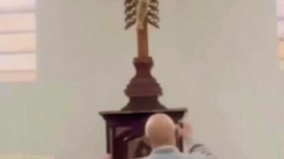 El sacerdote Óscar Echeverri cae al suelo después de que una cruz le golpeara la cabeza en Colombia.