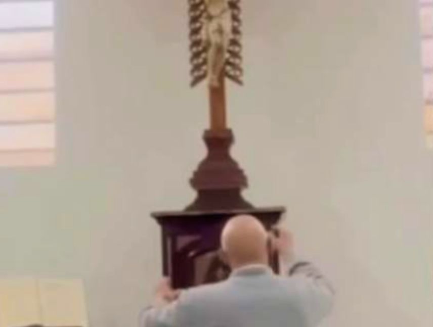 El sacerdote Óscar Echeverri cae al suelo después de que una cruz le golpeara la cabeza en Colombia.